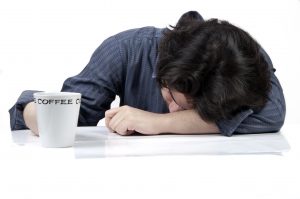 Tired man sleeping on table with cup of coffee