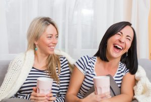 Two happy women laughing while sitting in bed at home